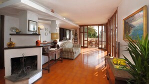 Amplia sala de estar con chimenea, comedor con mesa y sillas, y un gran ventanal con vistas al exterior.