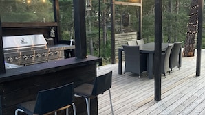 An outdoor patio with a grill, bar stools, and a covered seating area with string lights. - Comfortable living in modern seaview house with rooftop terrace (Tyresö)