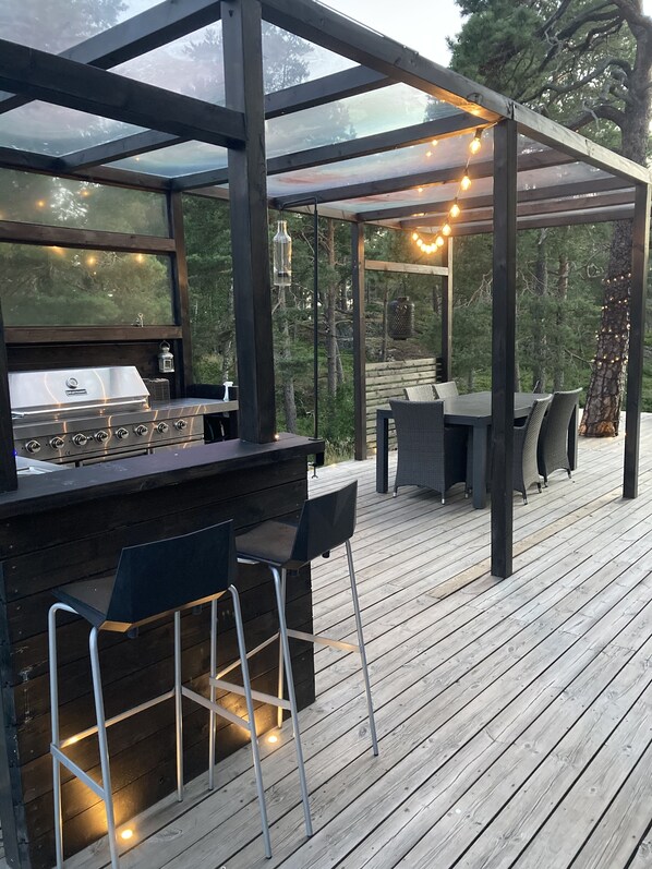 An outdoor patio with a grill, bar stools, and a covered seating area with string lights. - Comfortable living in modern seaview house with rooftop terrace (Tyresö)