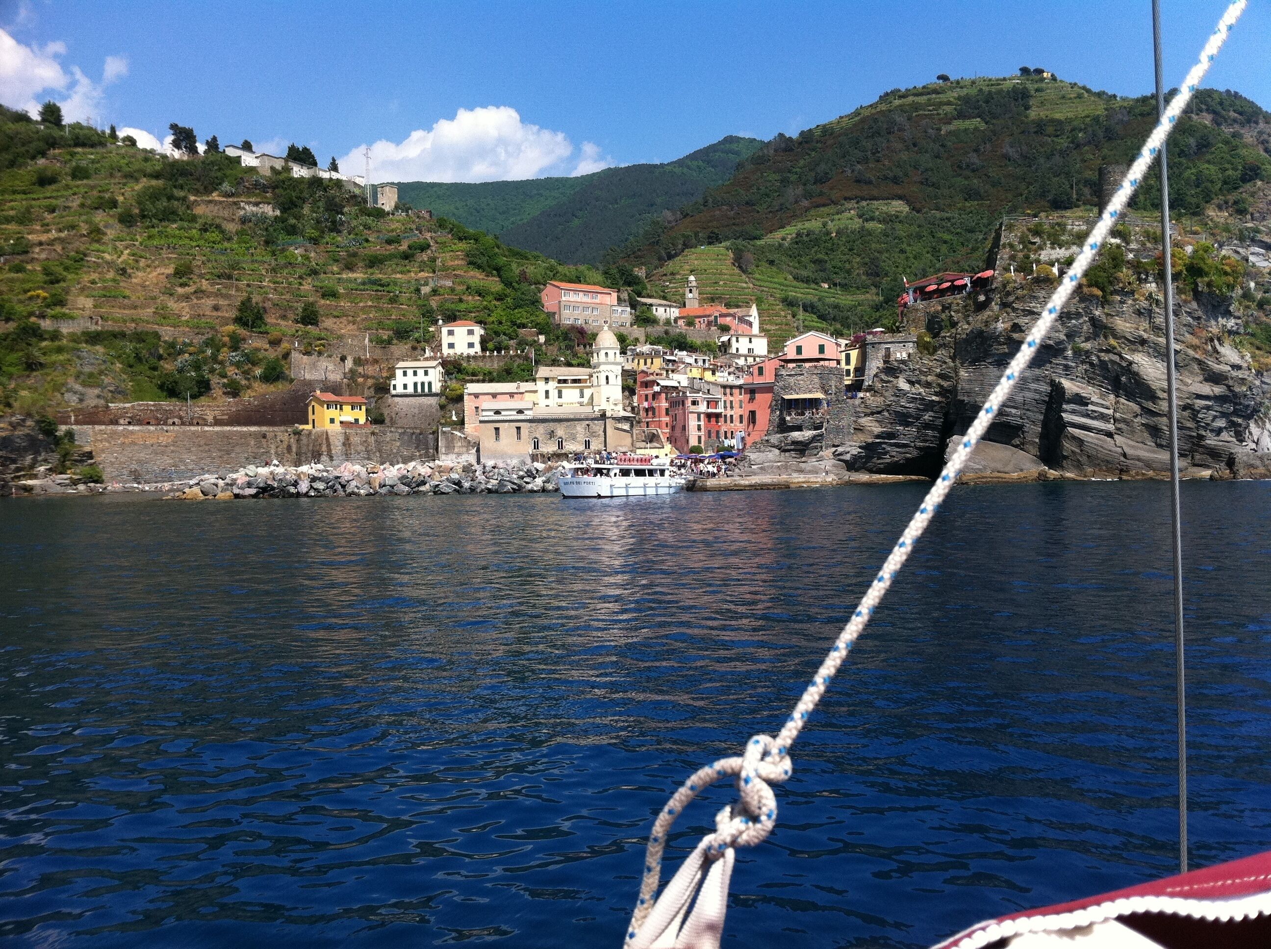 A coastal village with colorful buildings, a boat docked near the shore, and a rope in the foreground.
