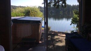 A room with a sliding glass door leading to a lake view, a small wooden shed, and a bench. - Cottage Lake Bed and Breakfast (Woodinville)