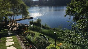 A serene lakeside setting with a wooden dock, stone steps leading to a gazebo, and lush greenery. - Cottage Lake Bed and Breakfast (Woodinville)