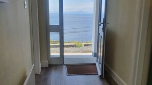 A hallway leading to a glass door with a view of the ocean.