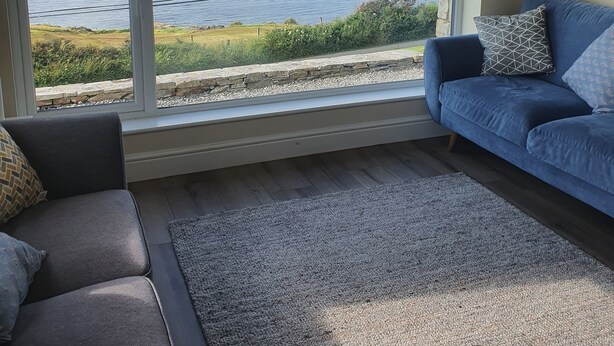 A living room with a large window offering a view of the sea and distant mountains.