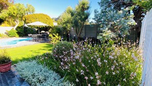 A backyard with a swimming pool, a barbecue area, and various plants and flowers. - Luxurious self-catering cottage sleeping up to 4 adults (Cape Town)
