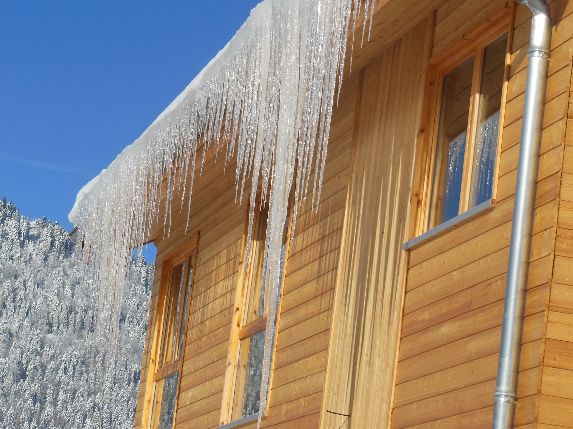 A wooden cabin with icicles hanging from the roof and windows.