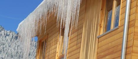 A wooden cabin with icicles hanging from the roof and windows.