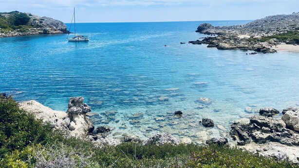 Eine Küstenlandschaft mit klarem, blauem Wasser, felsigen Ufern und einem Boot.