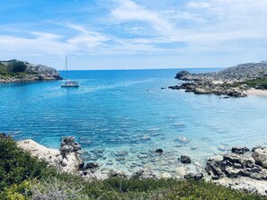 Eine Küstenlandschaft mit klarem, blauem Wasser, felsigen Ufern und einem Boot.