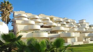 A multi-story hotel with balconies and a palm tree in the foreground.