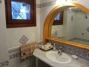Une salle de bain avec un lavabo blanc, un miroir doté d’un cadre en arc de cercle et des carreaux décoratifs.