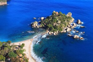 An aerial view of a coastal area with a small island featuring rocky terrain and a beach. - Suite Apartment Cavour- Exclusive"SunTripSicily" (Riposto)