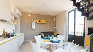 A modern kitchen with white cabinets, a dining area with white chairs, and a yellow bookshelf. - Suite Apartment Cavour- Exclusive"SunTripSicily" (Riposto)