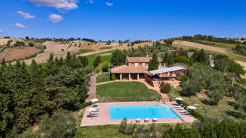 Una villa con piscina, immersa nel verde e circondata da dolci colline.