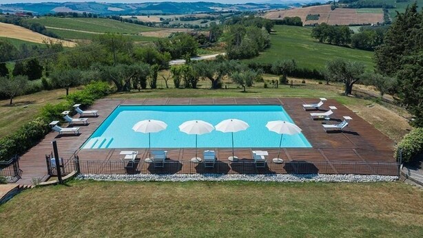 Ein rechteckiger Pool mit Holzboden und Liegestühlen.