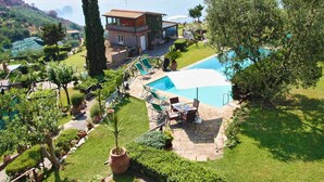 A villa with a swimming pool, outdoor seating, and a view of the surrounding landscape.