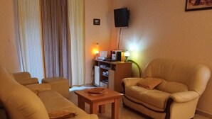 Een woonkamer met beige banken, een houten salontafel en een televisie op een dressoir.