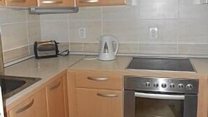 Een keuken met houten kasten, een roestvrijstalen fornuis en een waterkoker.