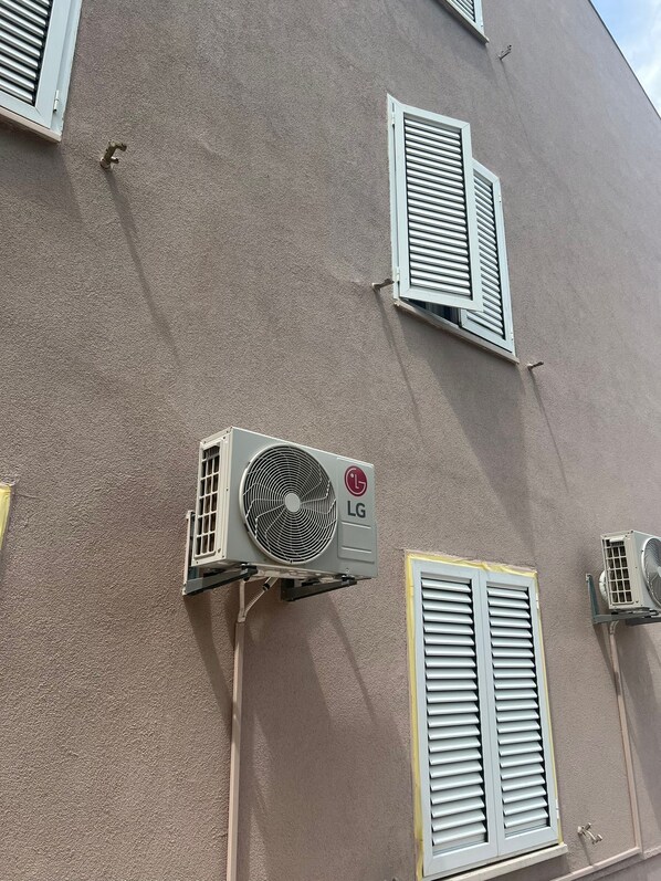 A building with multiple air conditioning units mounted on the exterior wall, including an LG unit.