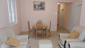 Een woonkamer met een witte bank, een eettafel met stoelen en een schilderij aan de muur.