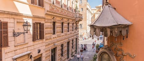A narrow street with historic buildings, a covered passageway, and a prominent statue.