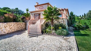 Une maison à deux étages avec un mur en pierre, un escalier et un jardin.