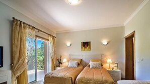 Une chambre avec deux lits, un canapé, une télévision et un balcon avec des rideaux.