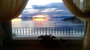 A view from a balcony with a railing, curtains, and two potted plants. - Apartment with stunning sea views (Podgora)