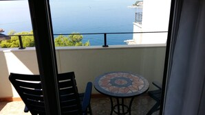 A balcony with a view of the sea, a tiled table, and two chairs. - Apartment with stunning sea views (Podgora)