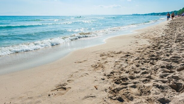 Une plage de sable avec des empreintes et un ciel bleu dégagé.