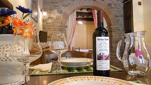 A dining table set with a bottle of wine, a pitcher, and a vase of flowers. - Typical Tuscan style apartment (cortona)