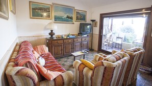 A living room with a sofa, armchairs, a TV, and a cabinet. There are three framed pictures on the wall. - VILLETTA BEL GIARDINO (MARINA DI CAMPO)