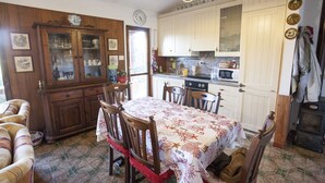 A traditional kitchen with wooden cabinets, a dining table with chairs, and a clock on the wall. - VILLETTA BEL GIARDINO (MARINA DI CAMPO)