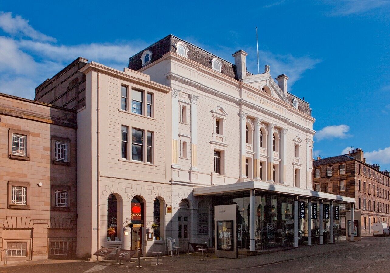 A historic building with a classical facade, a covered entrance, and a sign for 'The Royal Hotel'.
