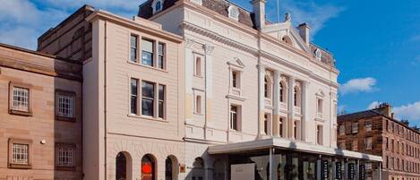 A historic building with a classical facade, a covered entrance, and a sign for 'The Royal Hotel'.