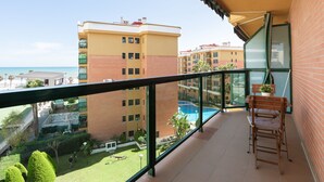 Een balkon met uitzicht op een zwembad, omliggende gebouwen en een heldere lucht.