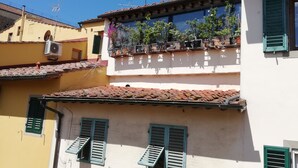 Un edificio con varios balcones, algunos con plantas y otros con contraventanas abiertas.