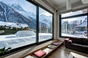 A modern living room with large windows, a sofa, and a bench.