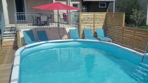 Piscina com água azul, rodeada por um deck de madeira e espreguiçadeiras.