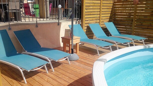 Uma área à beira da piscina com espreguiçadeiras e uma banheira de hidromassagem.