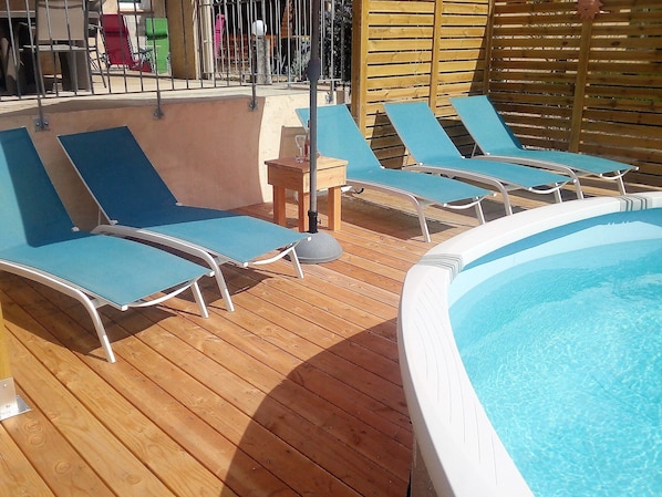 Un espace aménagé au bord de la piscine, avec des chaises longues et un jacuzzi.