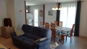 Un salon comprenant un canapé, une table à manger avec des chaises, un buffet en bois et une horloge murale.