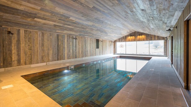 Una piscina interior amplia con paredes de madera y techo inclinado.
