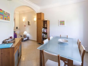 A dining area with a glass table and wooden chairs, a bookshelf, and a lamp. - Casa Sorriso, set in Boavista Golf Resort (Lagos)