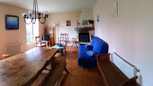 Una sala de estar acogedora con una mesa de comedor de madera, un sofá azul y una chimenea.