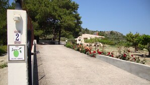Ein Weg, der zu einem Gebäude führt, mit einem Schild, auf dem 'The Olive Grove' und die Zahl '2' stehen.