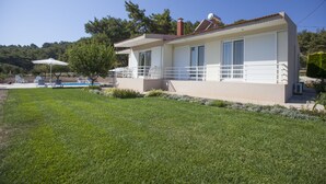 Ein zweistöckiges Haus mit Balkon, Schwimmbad und gepflegtem Rasen.