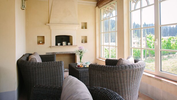 A cozy room with wicker furniture, a fireplace, and a large window offering a view of greenery. - Delicious Villa with wellness center and private pool (Camaiore)