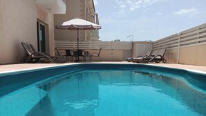 Piscina com espreguiçadeiras e um guarda-sol.