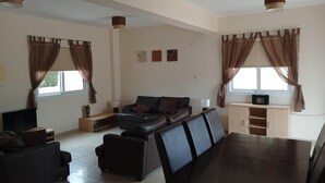 Uma sala de estar moderna com uma mesa de jantar de madeira escura, dois sofás e uma televisão.